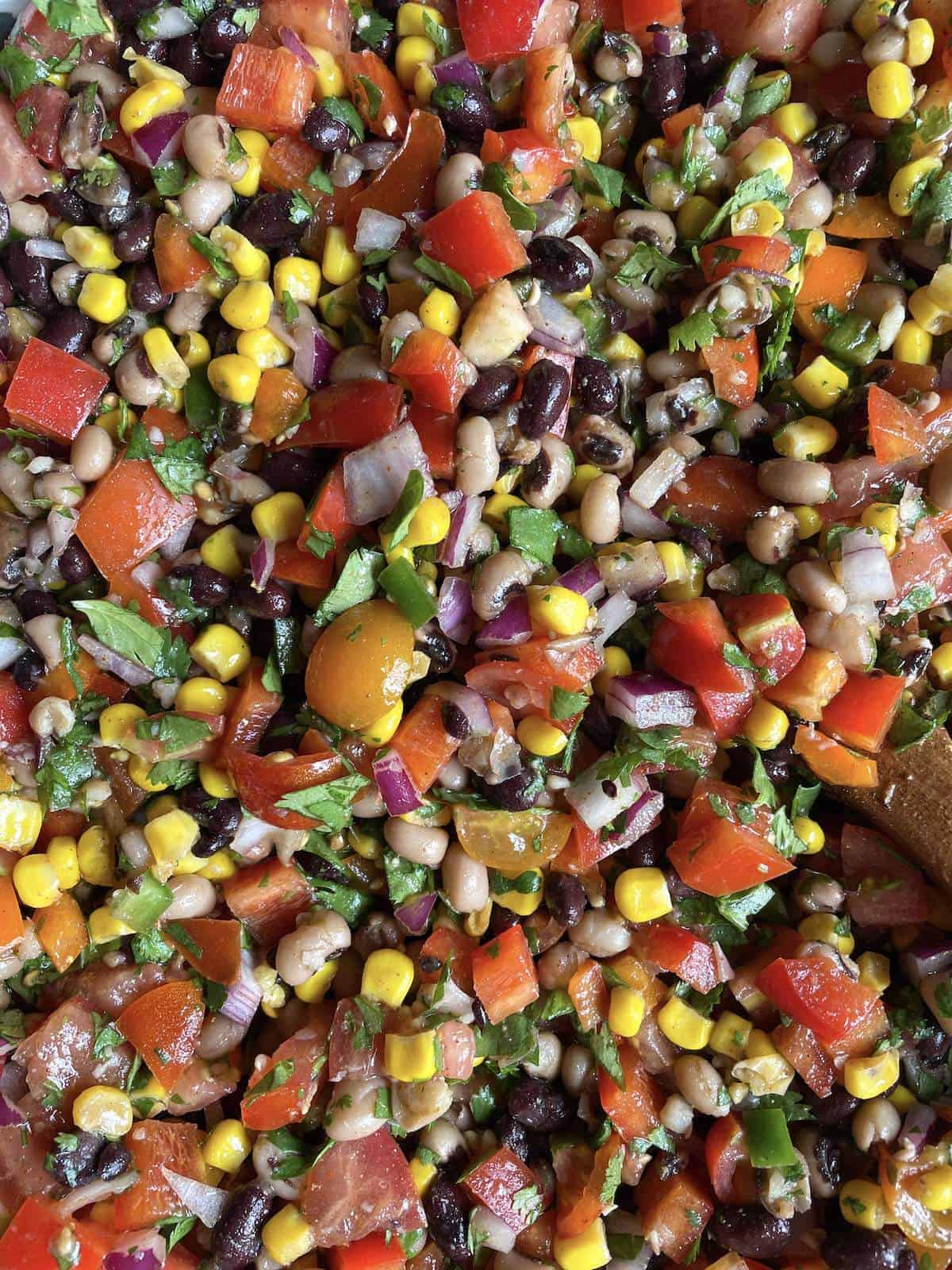 Cowboy caviar up close - black-eyed peas, black beans, corn, tomatoes, and peppers with a vinegar based dressing.