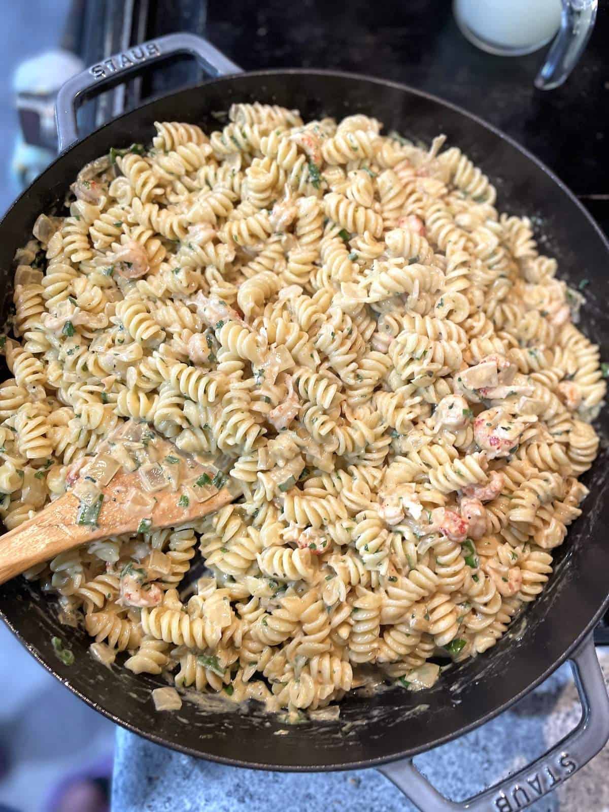 A skillet filled with rotini pasta, crawfish, and creamy crawfish monica sauce.