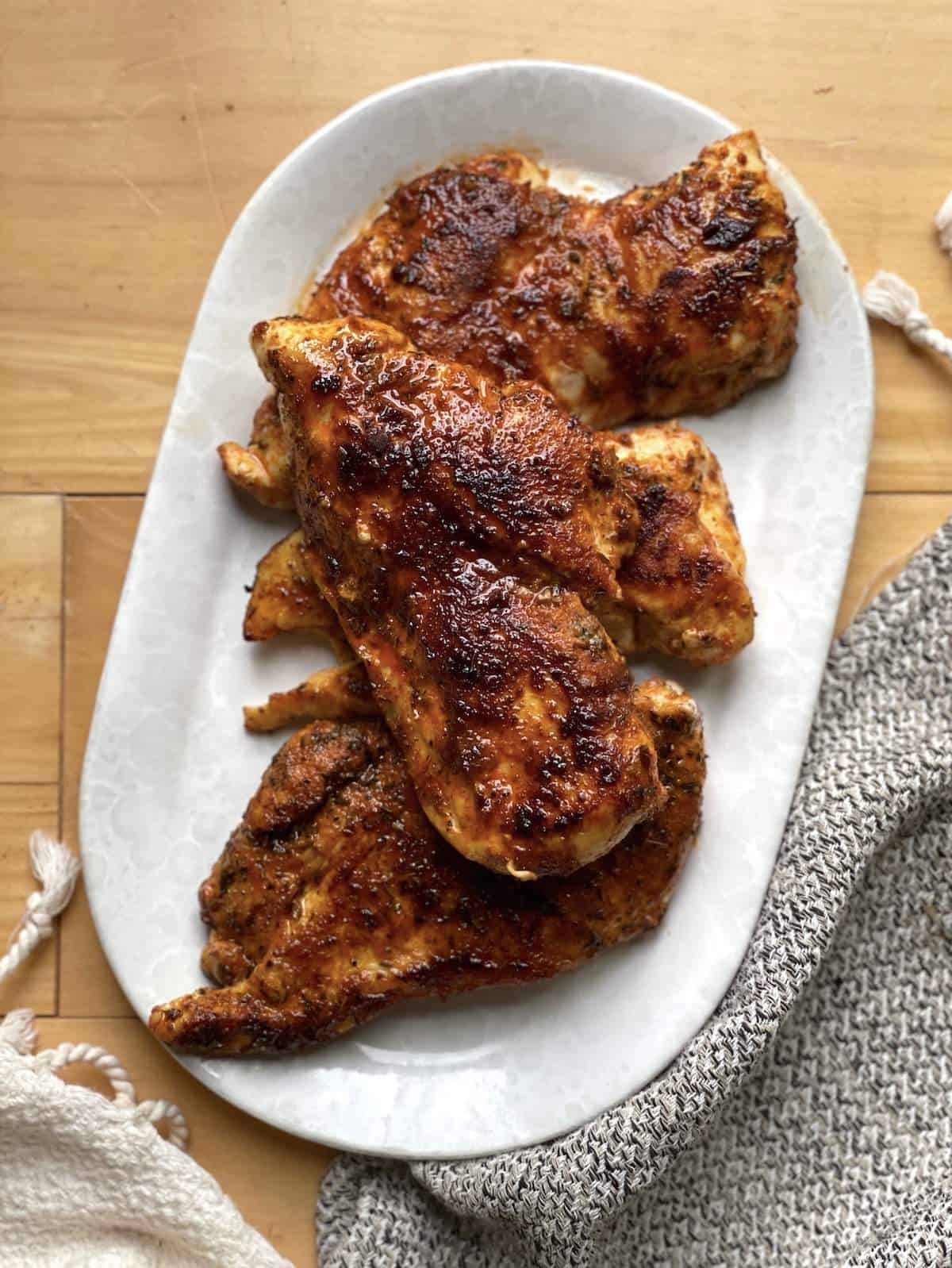 Cooked blacked chicken breasts on a white serving dish.