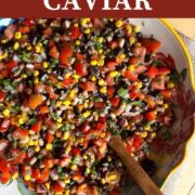 A pin image of a yellow of Texas caviar with black-eyed peas, black beans, corn, tomatoes, red onions, and cilantro with a vinegar based dressing with a wooden spoon.