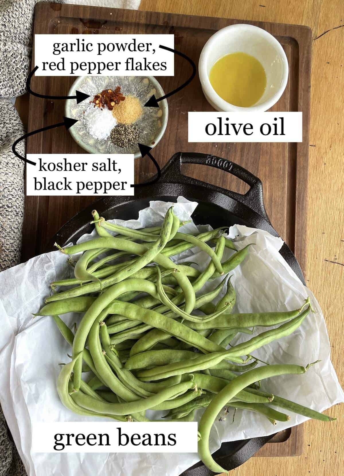 Ingredients needed to make air fryer green beans laid out and labeled - oil, spices, & green beans.