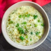 A small bowl of homemade egg drop soup topped with green onions.