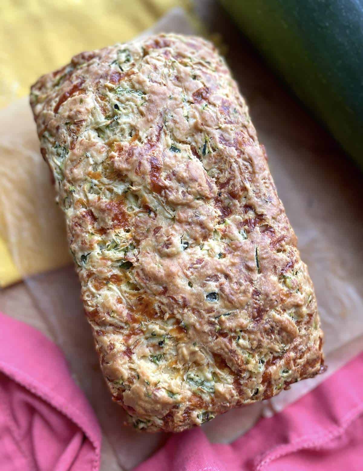 A loaf of baked cheesy, savory zucchini bread.