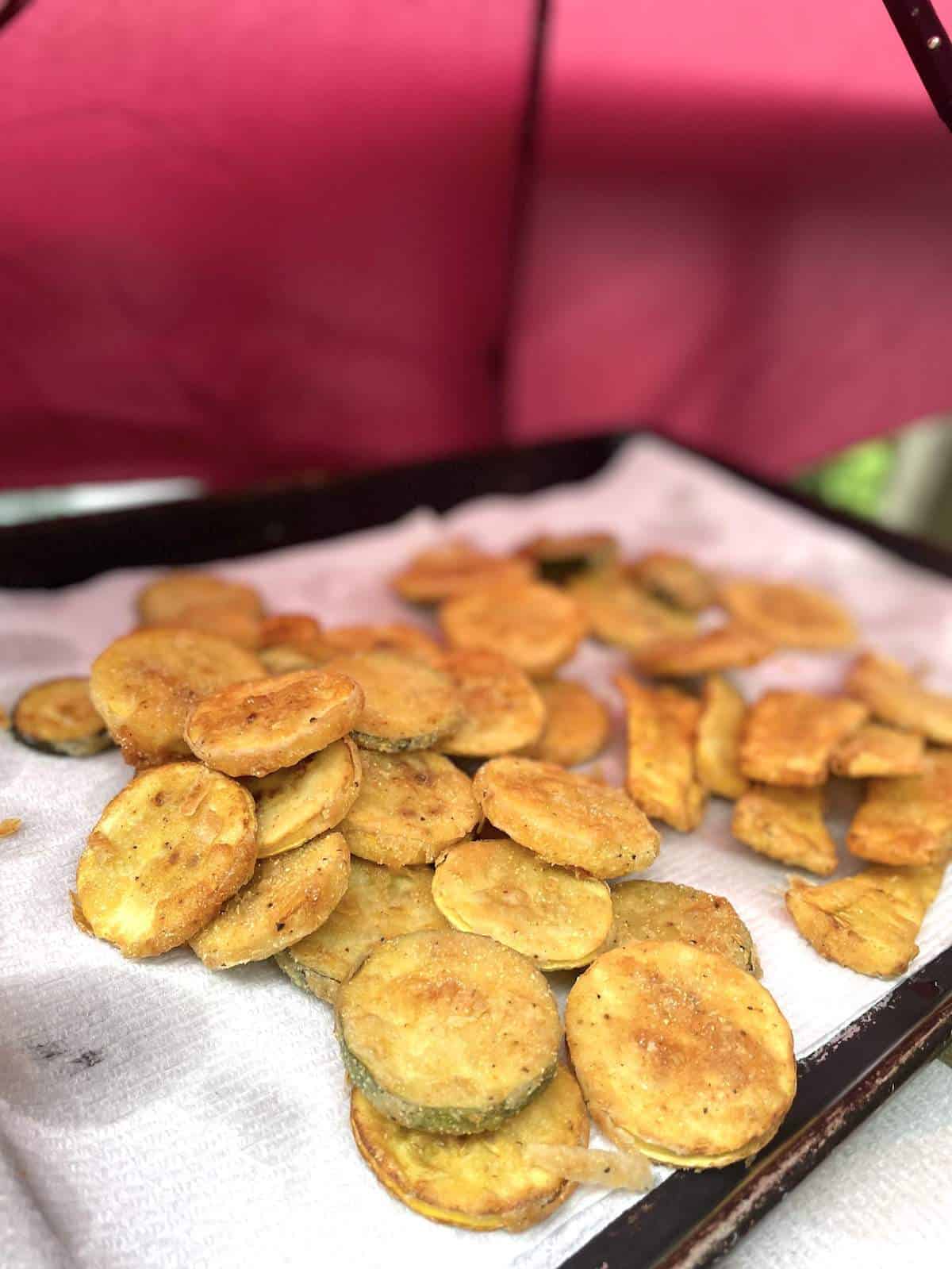 Fried squash slices and strips on a paper towel with an umbrella covering them.