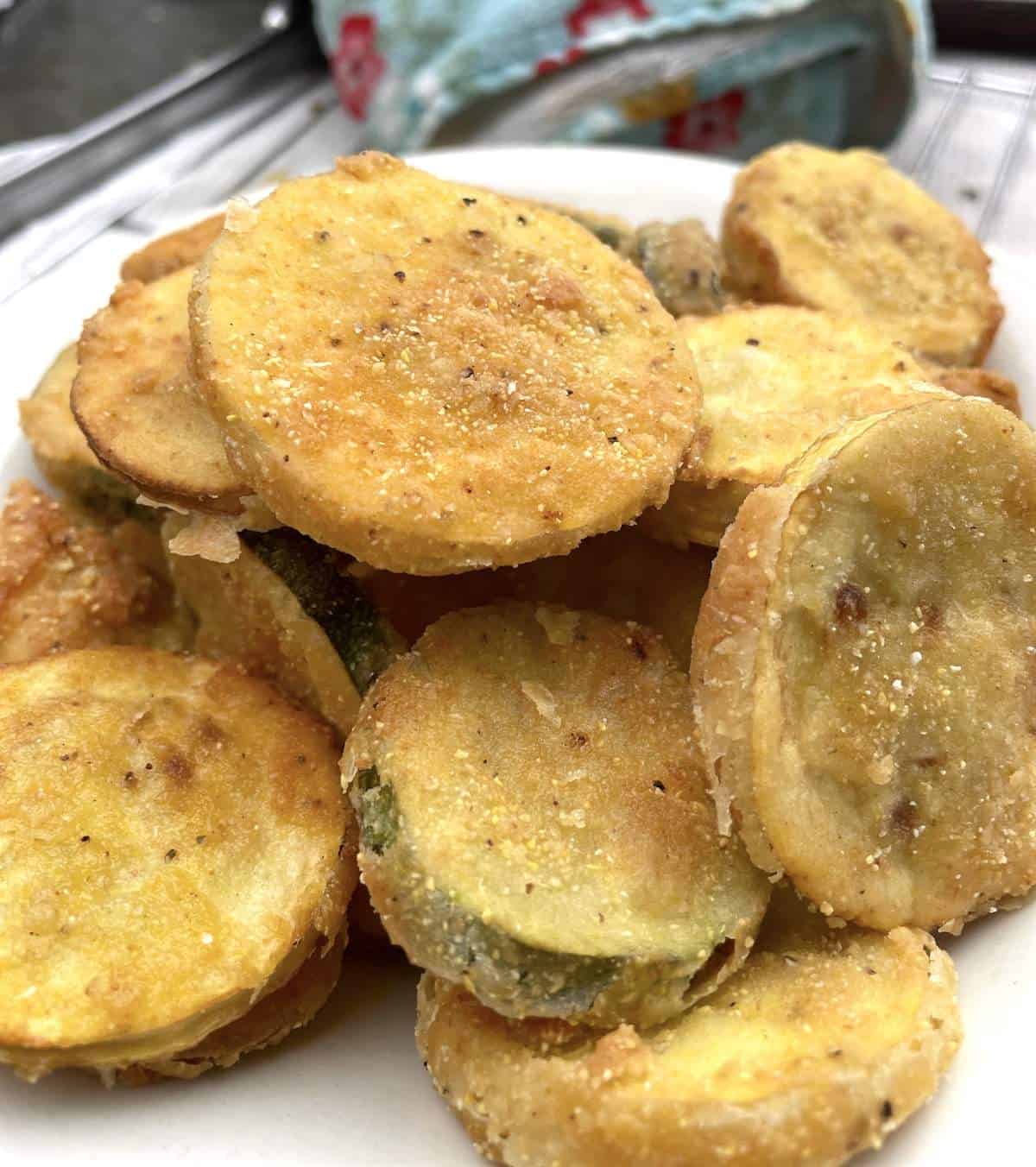 A white plate with deep fried squash and zucchini on it.