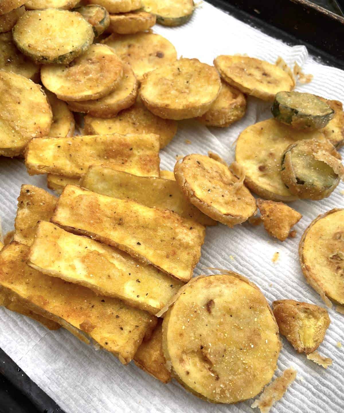 Fried squash strips and slices draining on a paper towel.
