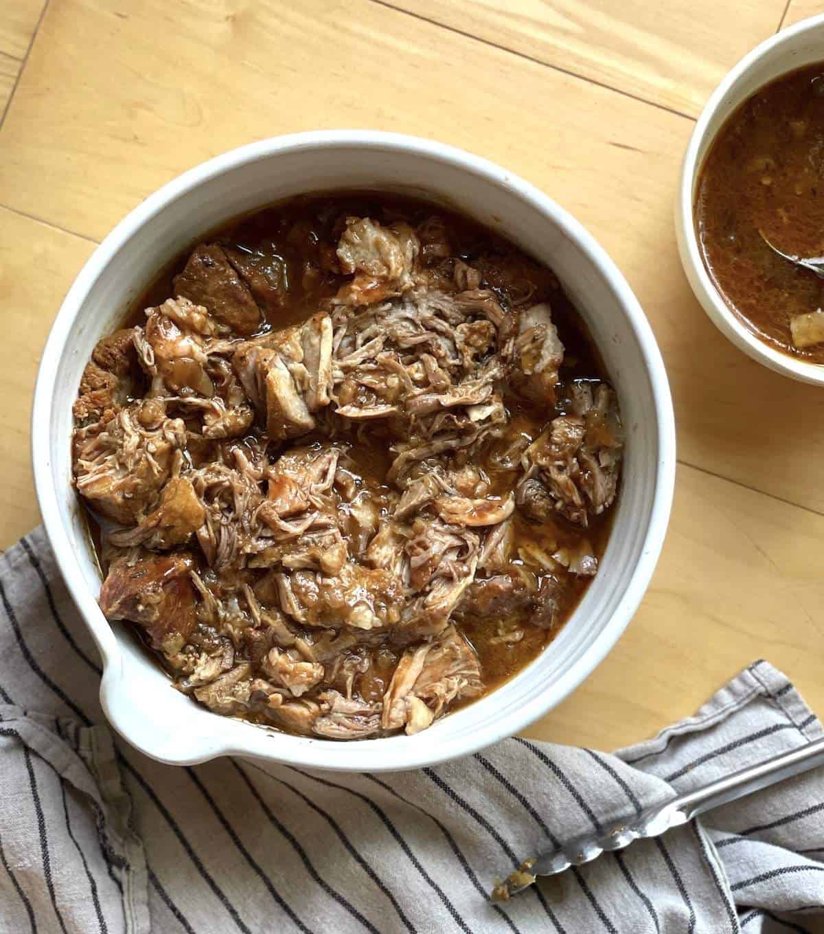 A white bowl of instant pot country style boneless ribs coated in broth and sauce.