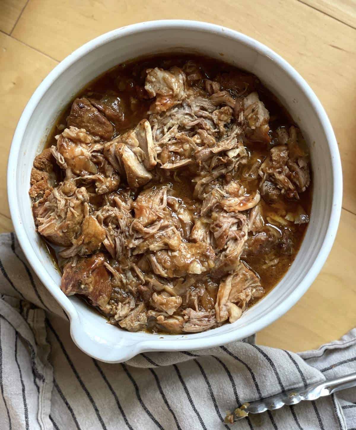 A white bowl of instant pot country style boneless ribs coated in sauce and broth.