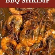 A pin image of New Orleans BBQ Shrimp smothered in sauce.