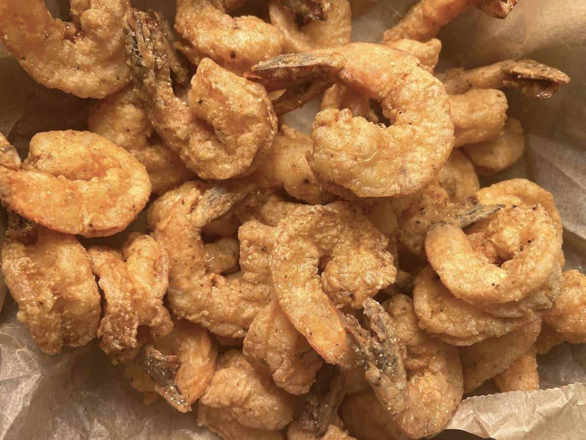 A pile of southern fried shrimp on top oof brown parchment paper.