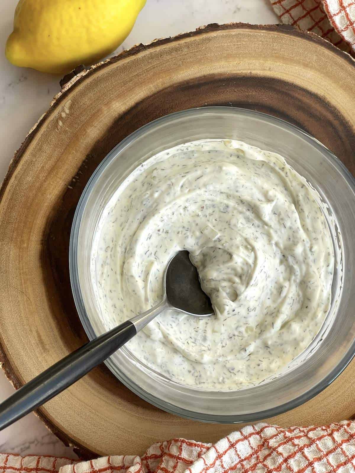 A bowl of homemade tartar sauce with a spoon in it.