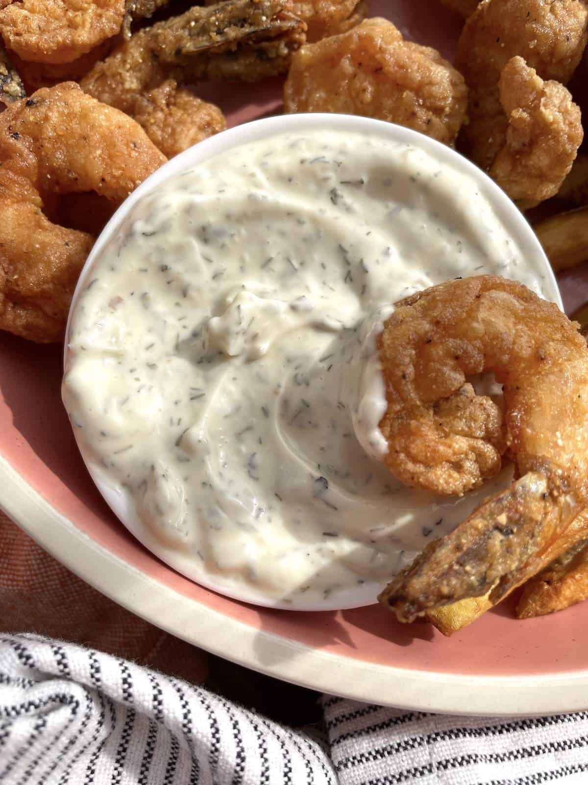 A bowl of fried shrimp with a small bowl of tartar sauce.