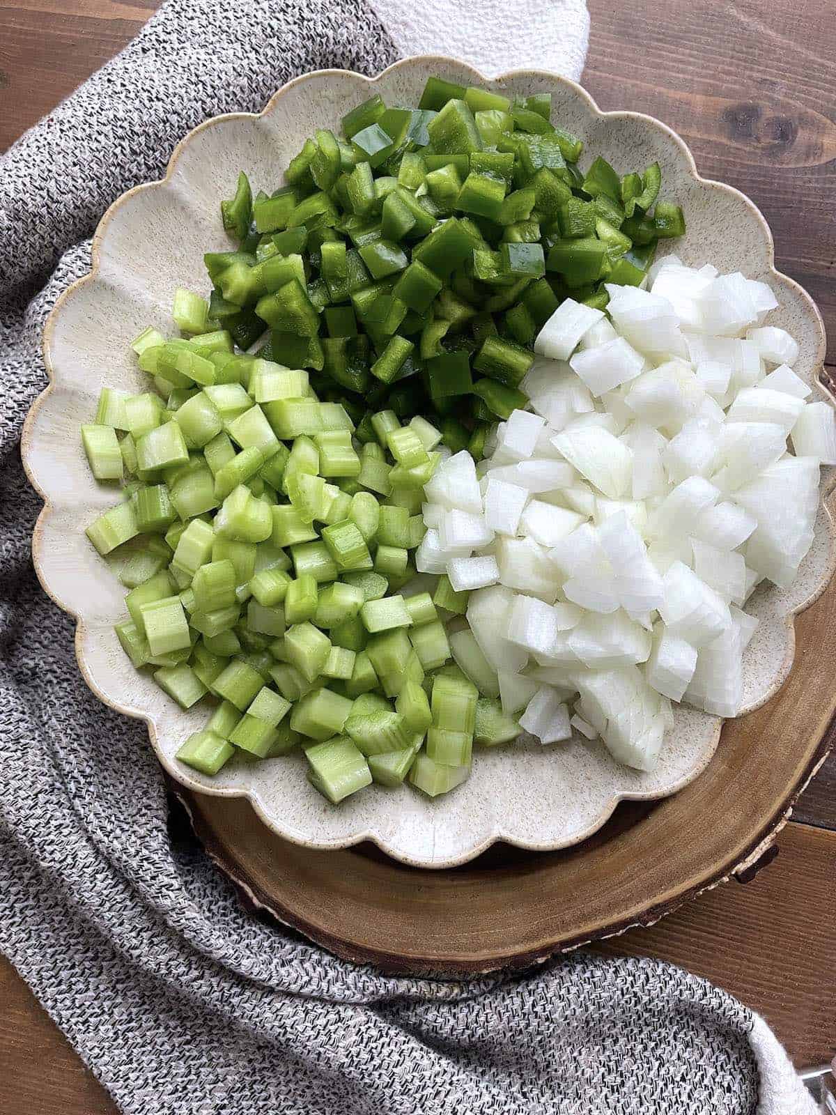 A plate with equal parts celery, onion, and green bell peppers to make the Cajun Holy Trinity.