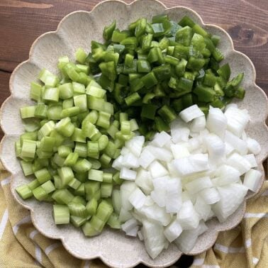 A plate with equal parts celery, onions, and bell peppers to make the Cajun holy trinity.