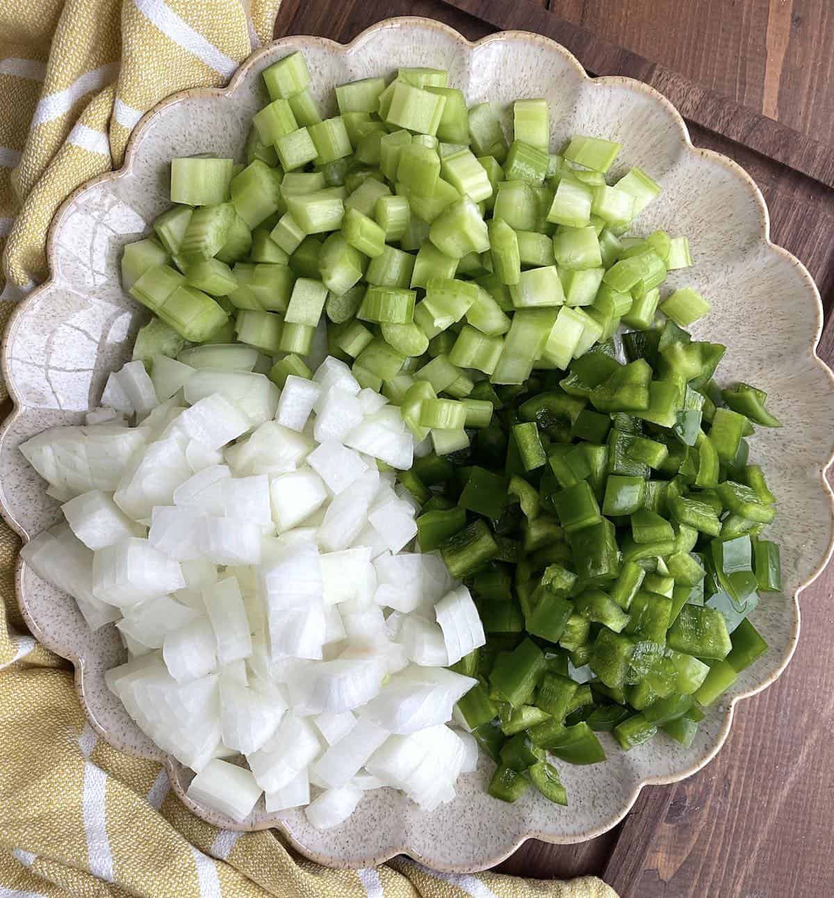 A plate with diced onions, green bell peppers, and celery to make a Cajun Holy Trinity.