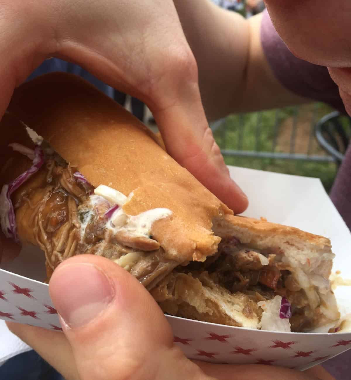 A man eating a slow roasted duck po boy at French Quarter Fest.