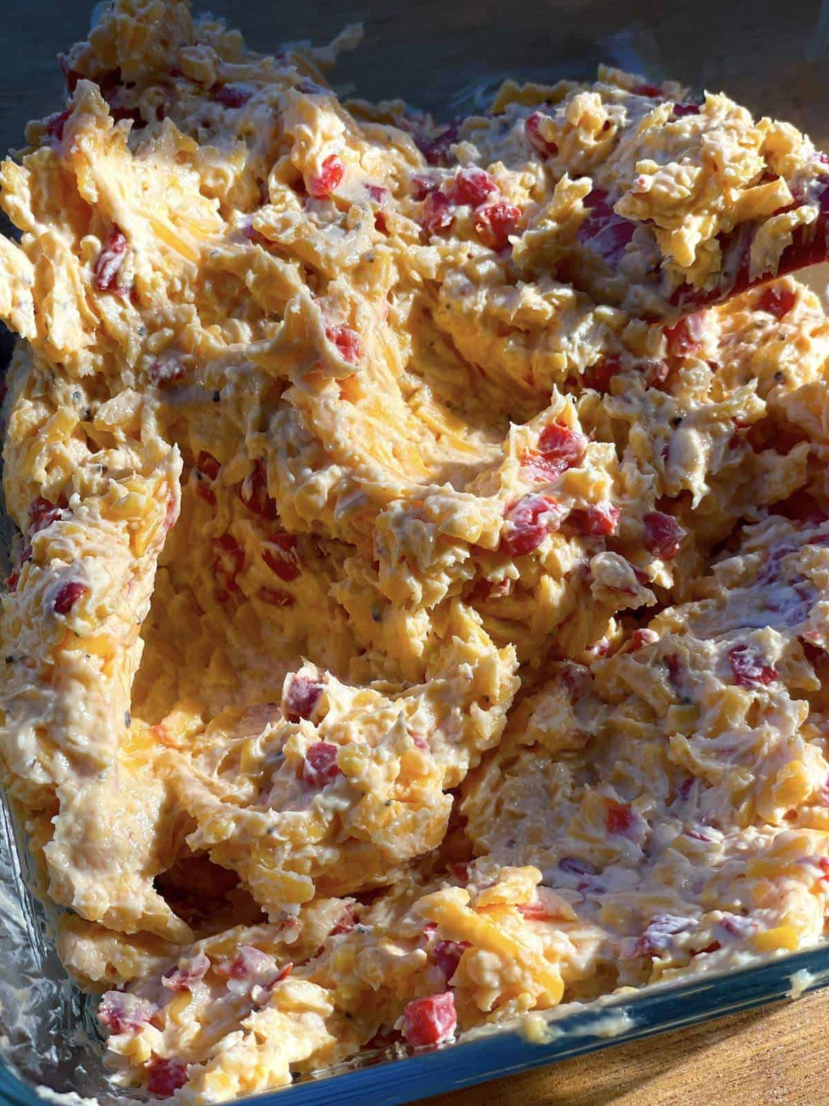 A glass container filled with homemade pimento cheese glistening in the sun.
