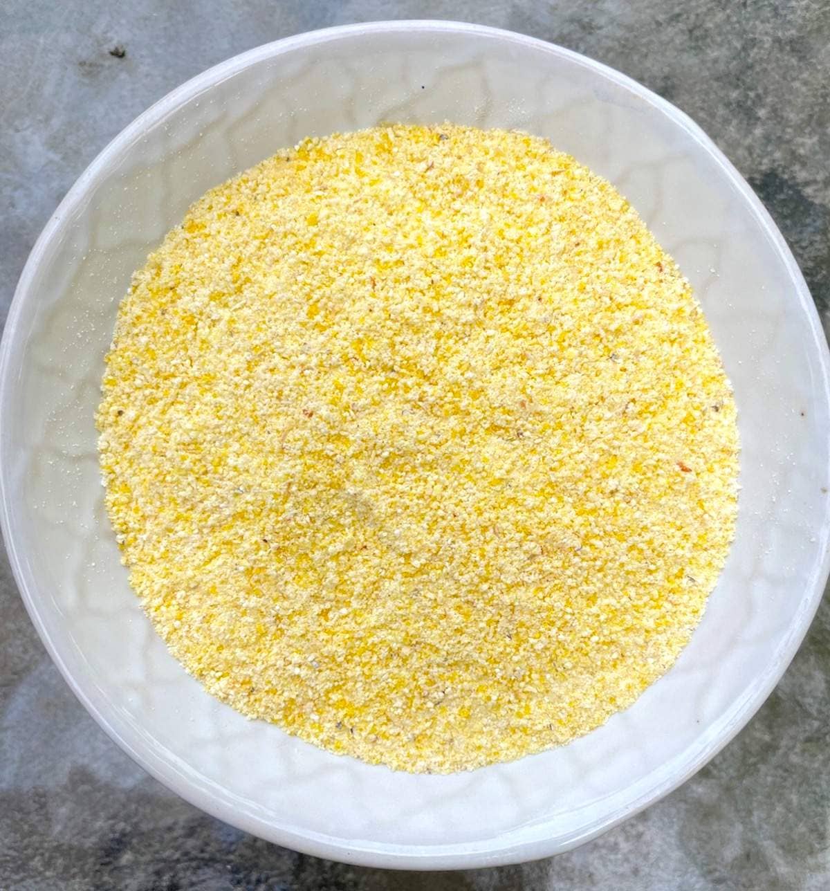 A small white bowl of yellow cornmeal.