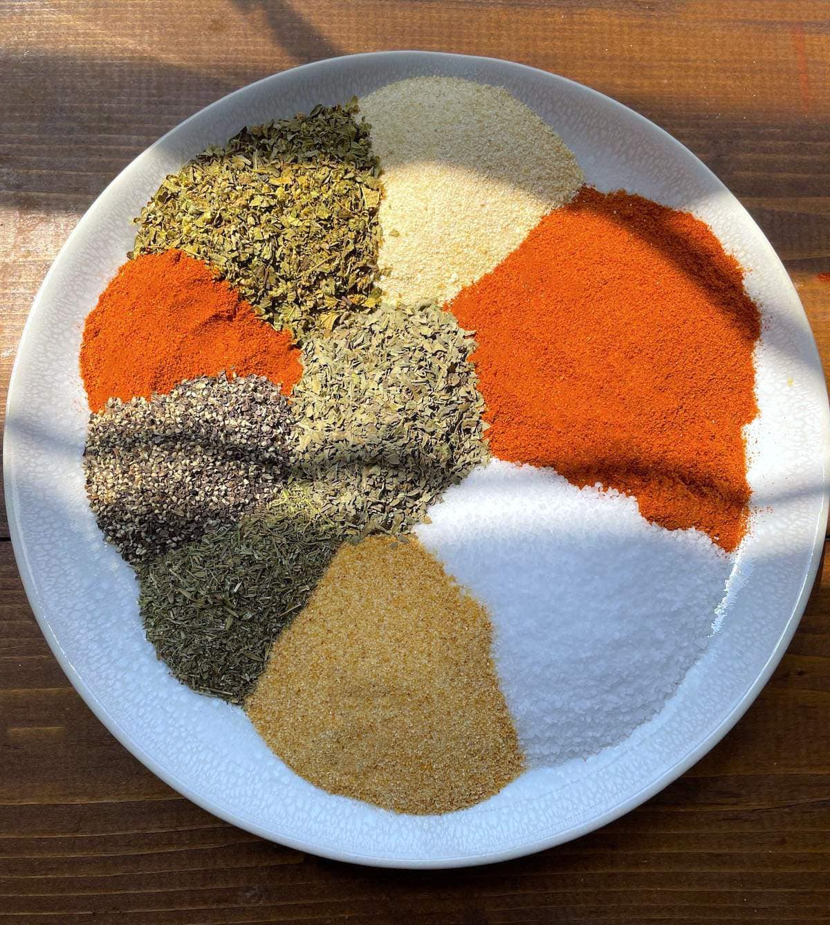 A white plate with the spices in Creole seasoning laid out on it.
