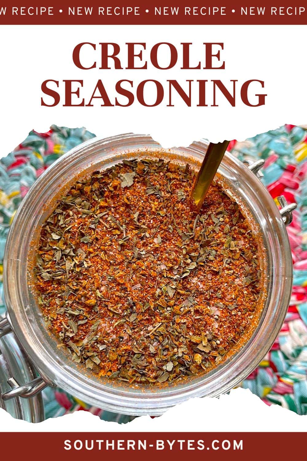 A pin image of a jar of homemade creole seasoning on a colorful mat with a gold spoon in the jar.