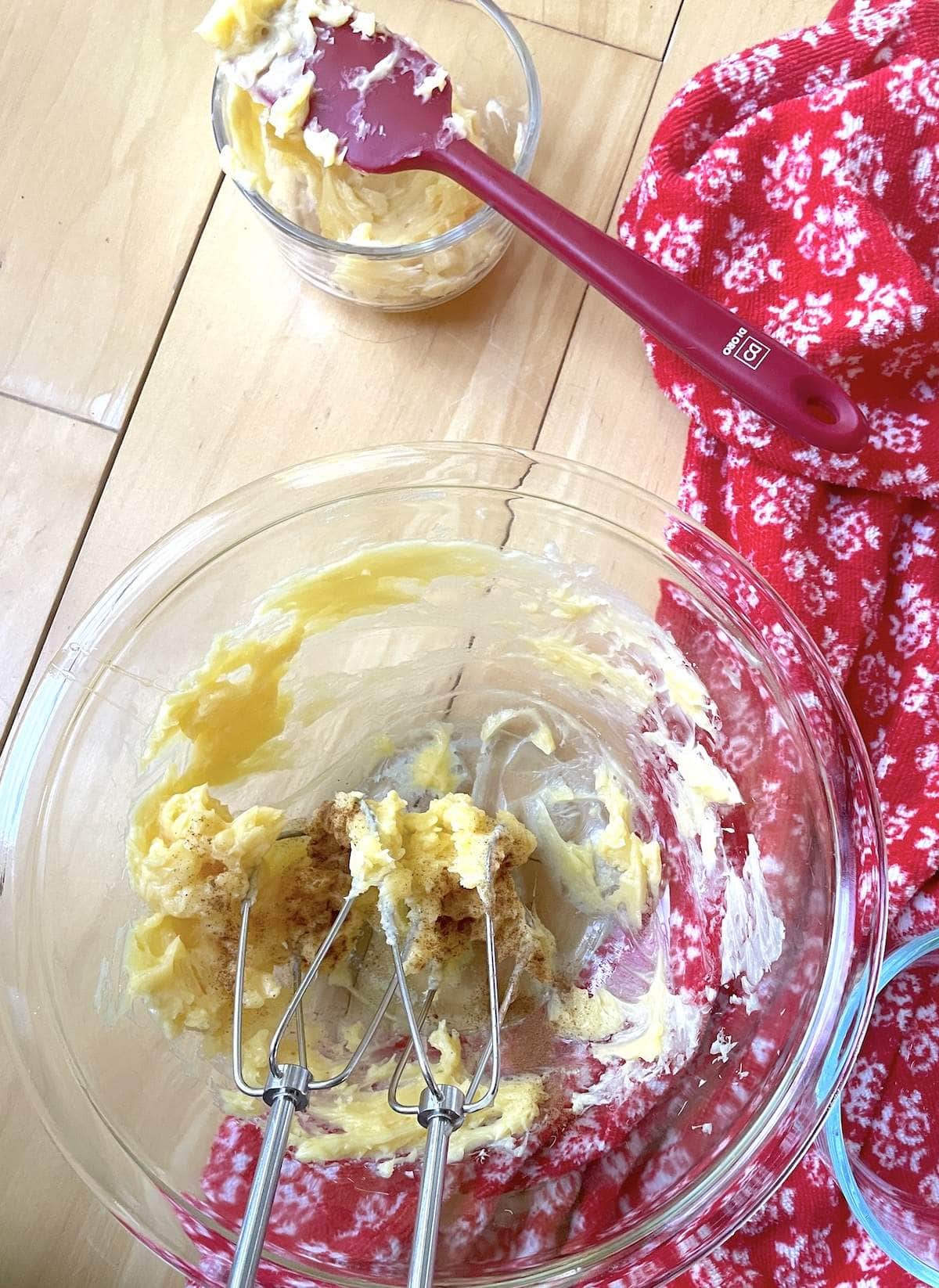 A small bowl of honey butter being whipped with an electric mixer, with cinnamon and vanilla extract being added to it after splitting from the plain honey butter.