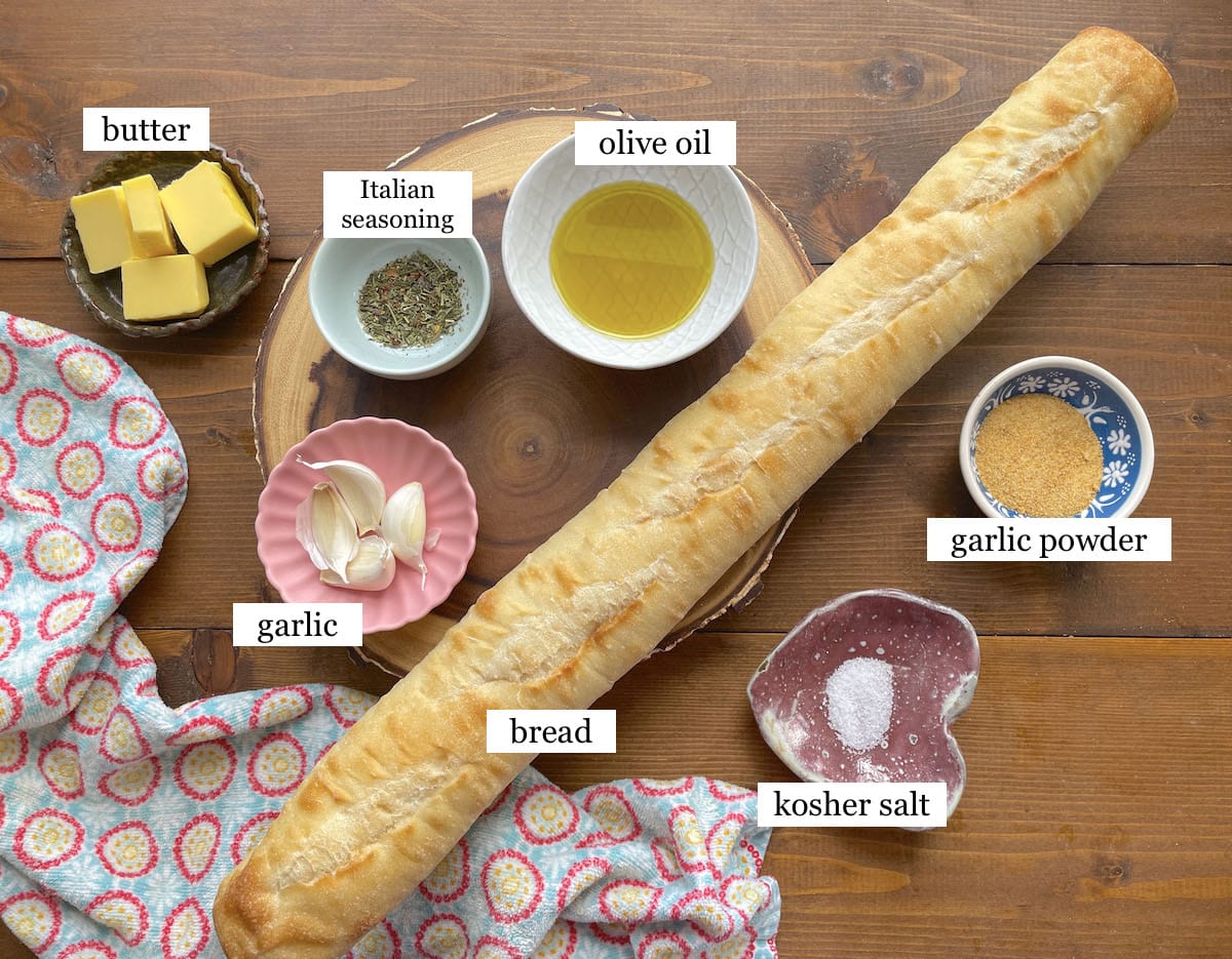 The ingredients needed to make garlic toast in small bowls, laid out and labeled.