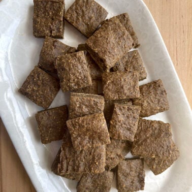 A white plate covered in square liver brownie treats for dogs.