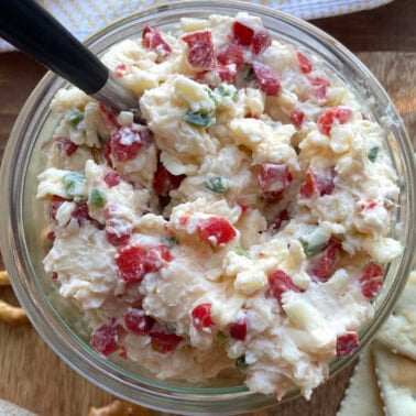 A bowl of creamy jalapeño pimento cheese made with white cheddar cheese with a spoon.