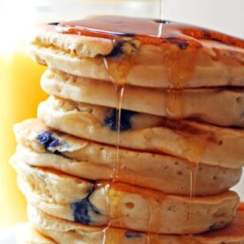 A stack of blueberry pancakes with syrup dripping down the side.