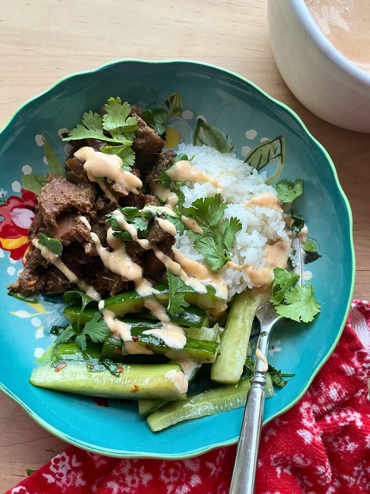 A blue bowl with rice, bulgogi, Korean pickles, Yum Yum sauce, and cilantro.