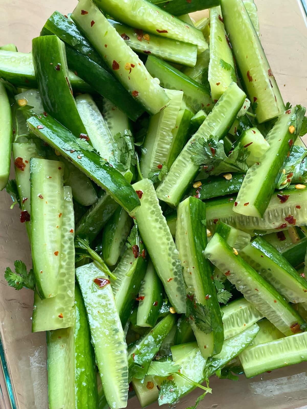 A glass bowl of slices of spicy Korean cucumber pickle spears.