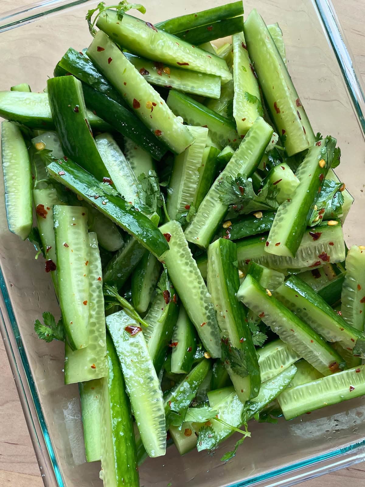 A glass bowl of slices of Korean cucumber pickle spears.