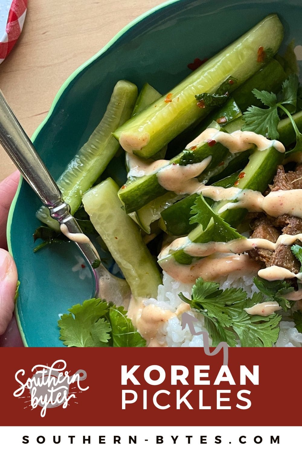 A pin image of a blue bowl with rice, bulgogi, Korean pickles, Yum Yum sauce, and cilantro, focused on the pickles.