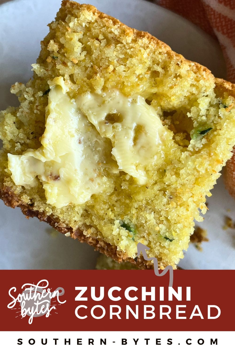 A pin image of a slice of zucchini cornbread on a white plate with honey butter melting on it.