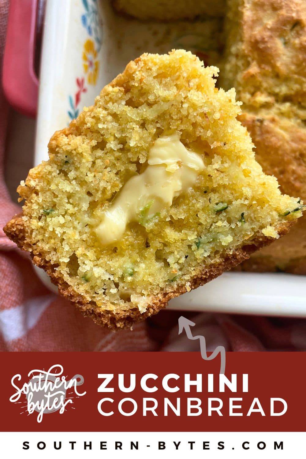 A pin image of a slice of zucchini cornbread sitting on the edge of a pan of cornbread with honey butter melting on it.