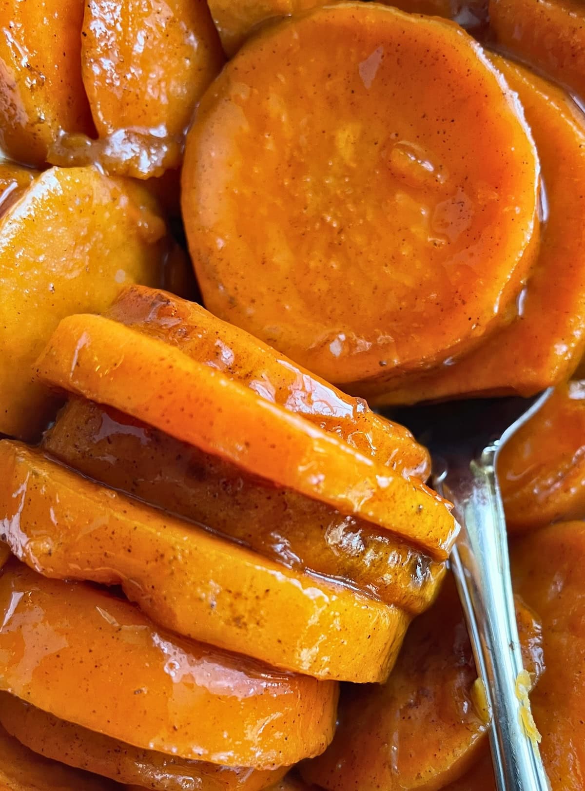 Close-up view of sliced candied sweet potatoes glazed with syrup.