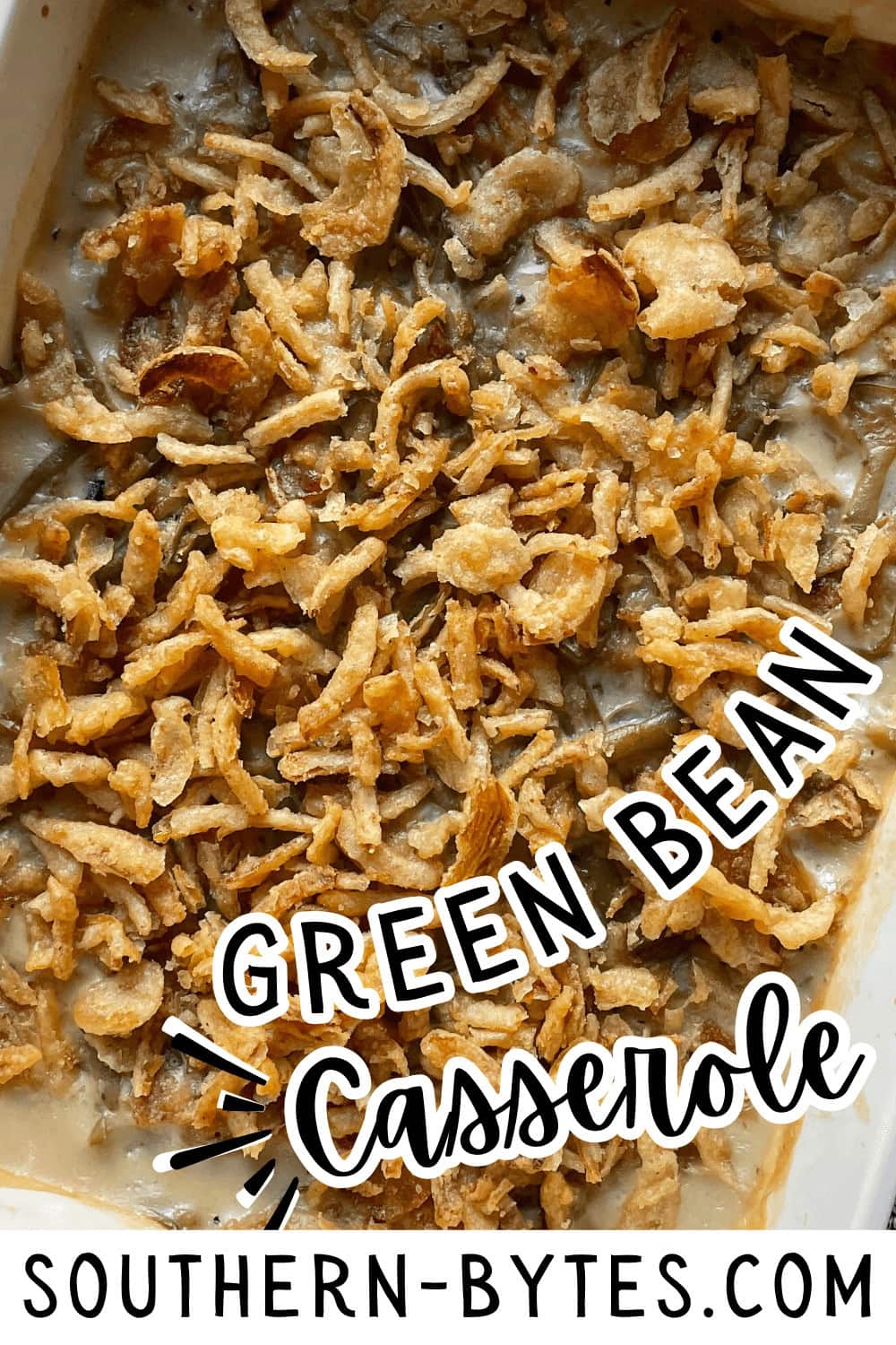 A pin image of a close-up of a green bean casserole topped with crispy fried onions.