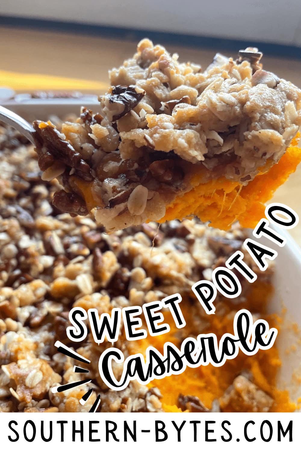 A pin image of a close-up of a forkful of sweet potato casserole with a pecan streusel topping.