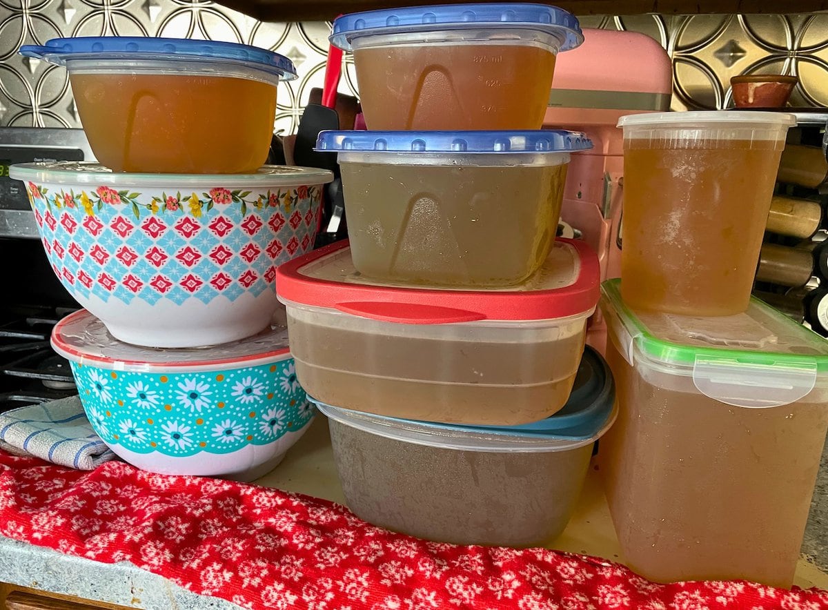 Various containers of homemade broth neatly arranged on a kitchen counter.