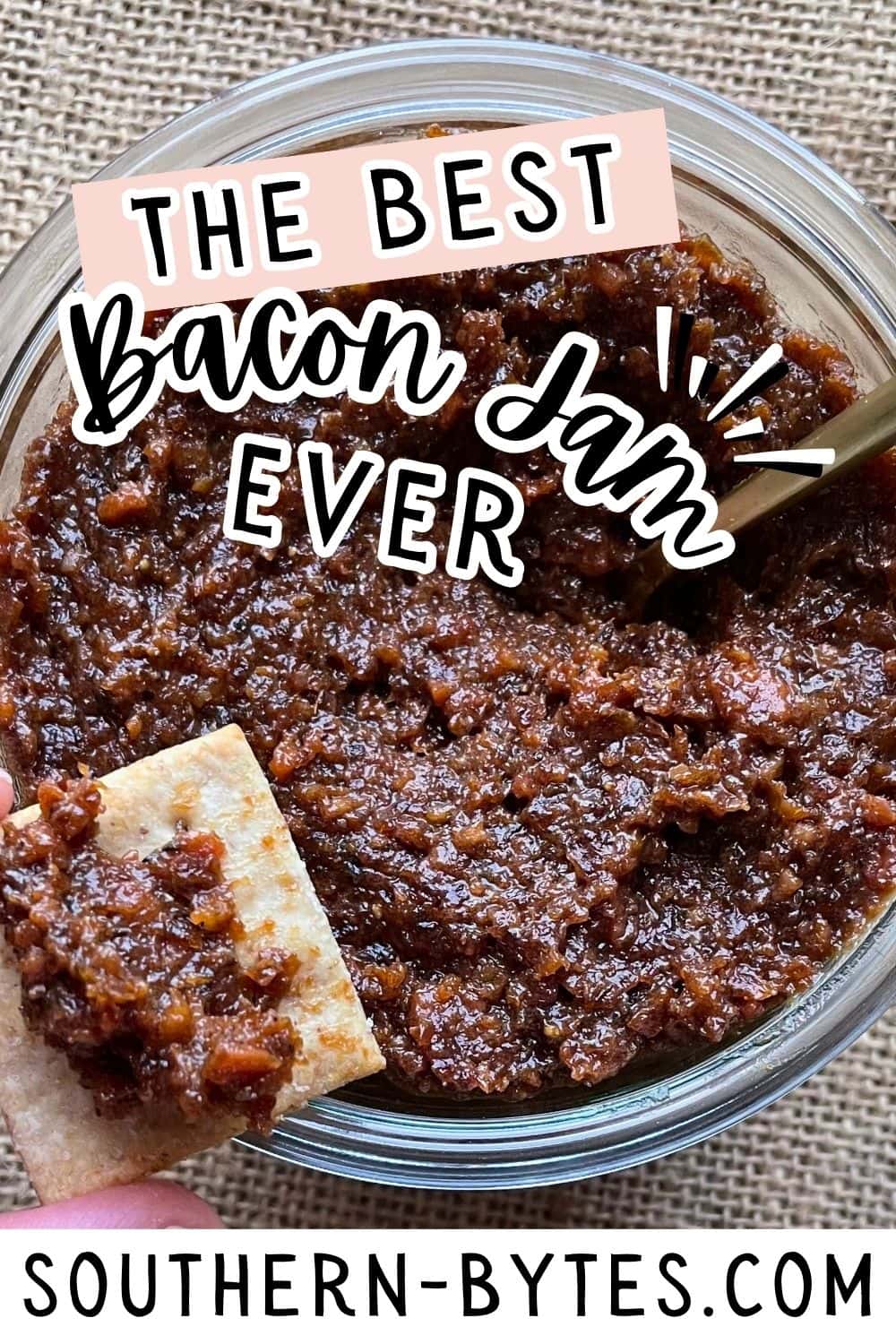 A pin image of a jar of homemade bacon jam with a cracker dipped in it.