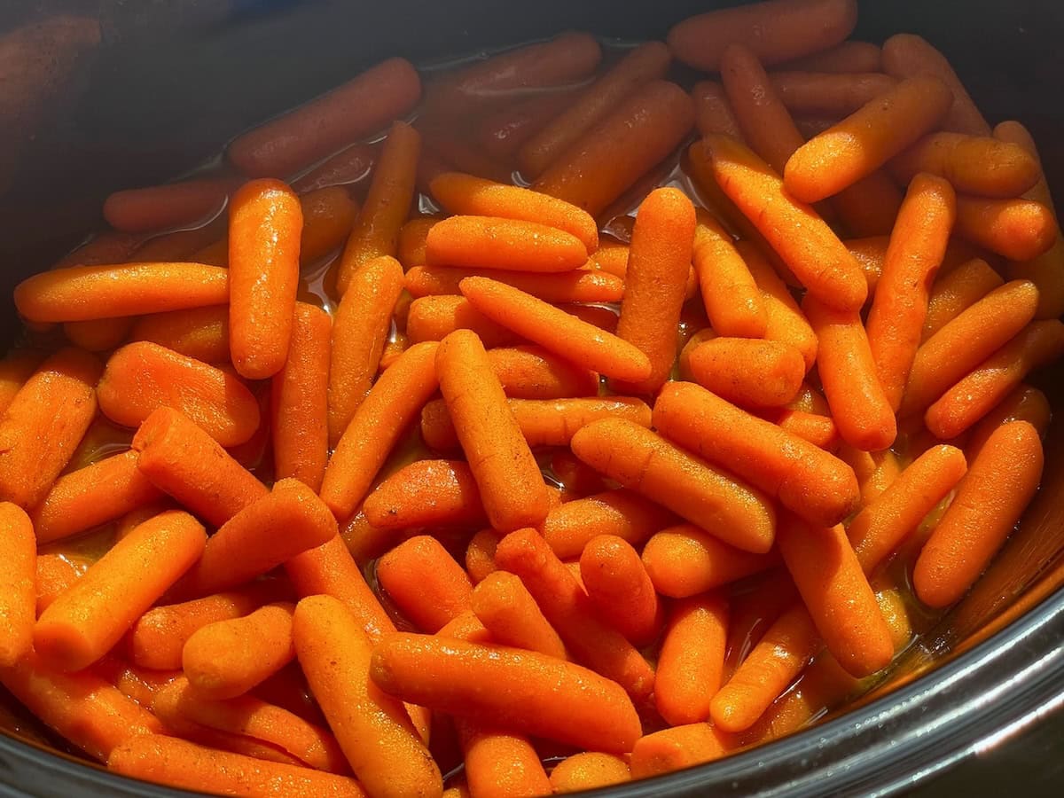 A close-up view of bright orange baby carrots cooked and served in a cooking pot.