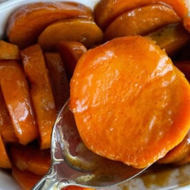 A close-up of glazed candied sweet potatoes in a white dish.