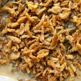 Close-up of a green bean casserole topped with crispy fried onions in a baking dish.