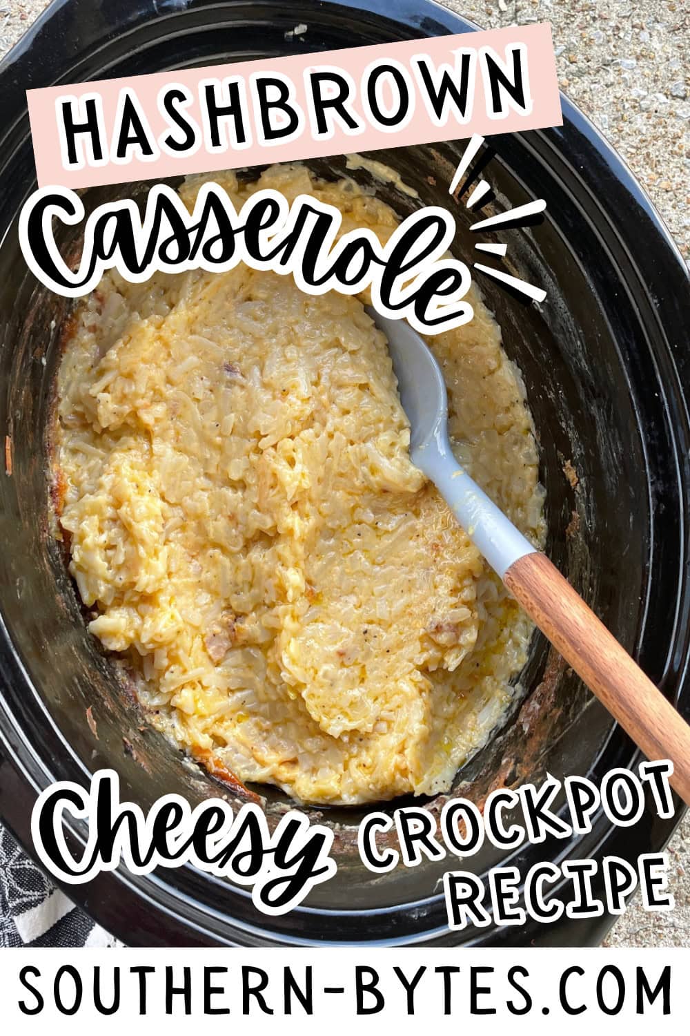 A pin image of a crockpot containing a cheesy hashbrown casserole with a serving spoon.