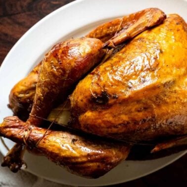 A succulent, golden-brown roast turkey presented on a white serving dish.