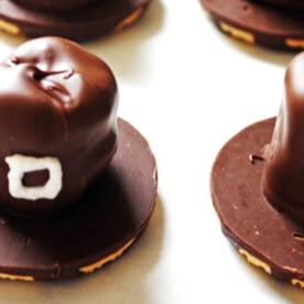 Several homemade chocolate-dipped marshmallow treats with cookie bases, decorated with white icing designs.