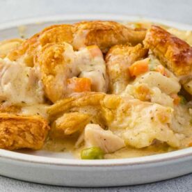 Close-up view of a chicken pot pie with creamy filling, vegetables, and flaky crust served on a plate