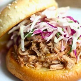 A delicious pulled pork sandwich topped with crunchy coleslaw, served on a sesame seed bun.