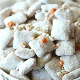 A close-up of a bowl filled with powdered sweet snack mix, featuring small, sugar-coated pieces and colorful sprinkles.