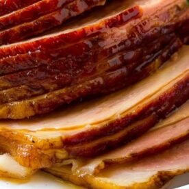 Close-up of beautifully sliced glazed ham with caramelized edges, showcasing a golden brown sheen and tender texture.